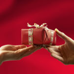 Close-up of red gift, giving from man to woman