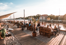 Menschen sitzen bei Sonnenschein unter freiem Himmel am Kieler Sandhafen